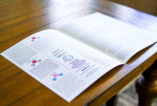 Paper publication, opened so the inner spread is visible, on a wooden table